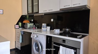 Kitchen interior with white cabinets, oven, washing machine and microwave