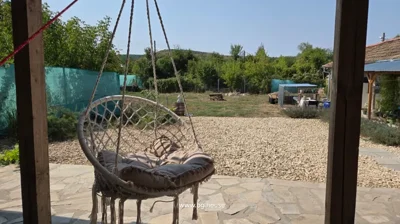 Hanging chair with cushion on stone patio overlooking garden area with gravel and greenery