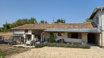 Single-storey building with tiled roof, covered patio area with table, chairs, and various items outside