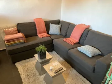 Gray corner sofa with cushions and folded blankets in a living room setting.